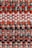 A colorful, tightly woven textile pattern composed of alternating bands of various fabrics. The materials are intricately interlaced, featuring warm hues like reds, oranges, and pinks with accents of teal and black. The texture appears rich and tactile, indicative of handcrafted artistry.