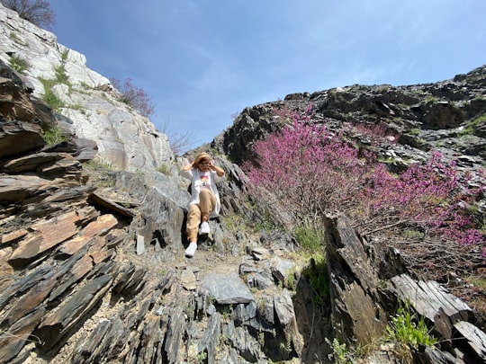 woman in white tank top and white shorts sitting on brown rock formation during daytime in Razavi Khorasan Province Iran