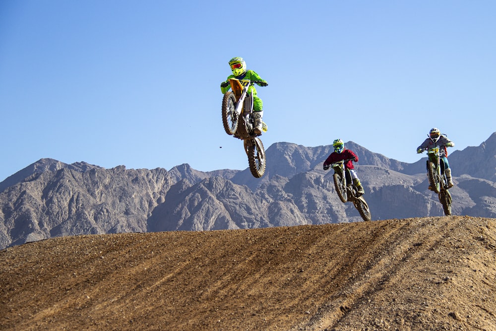 man in green jacket riding motocross dirt bike on green grass field during daytime