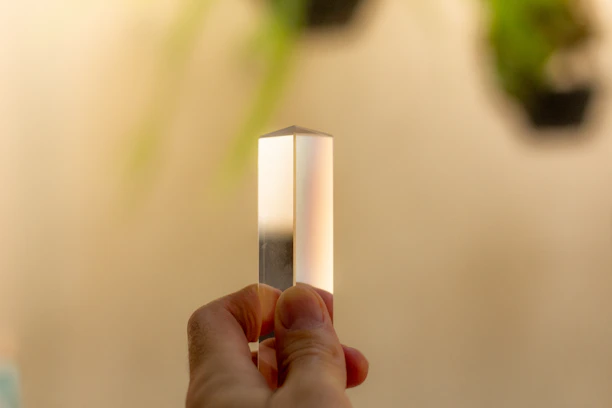A close-up of hands gently holding a small, glowing crystal surrounded by natural greenery.