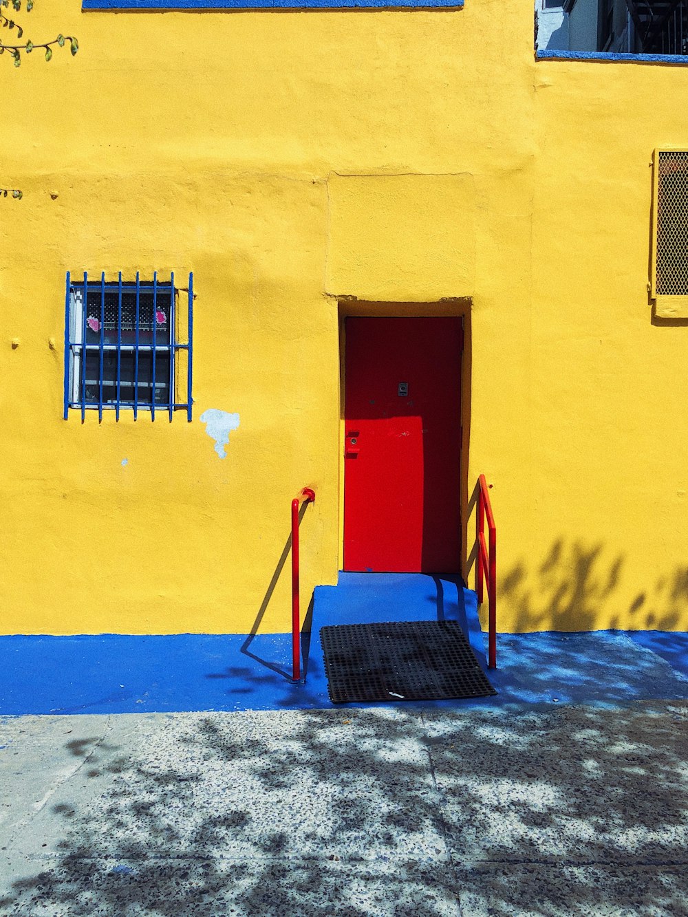 red and blue wooden chair beside yellow painted wall