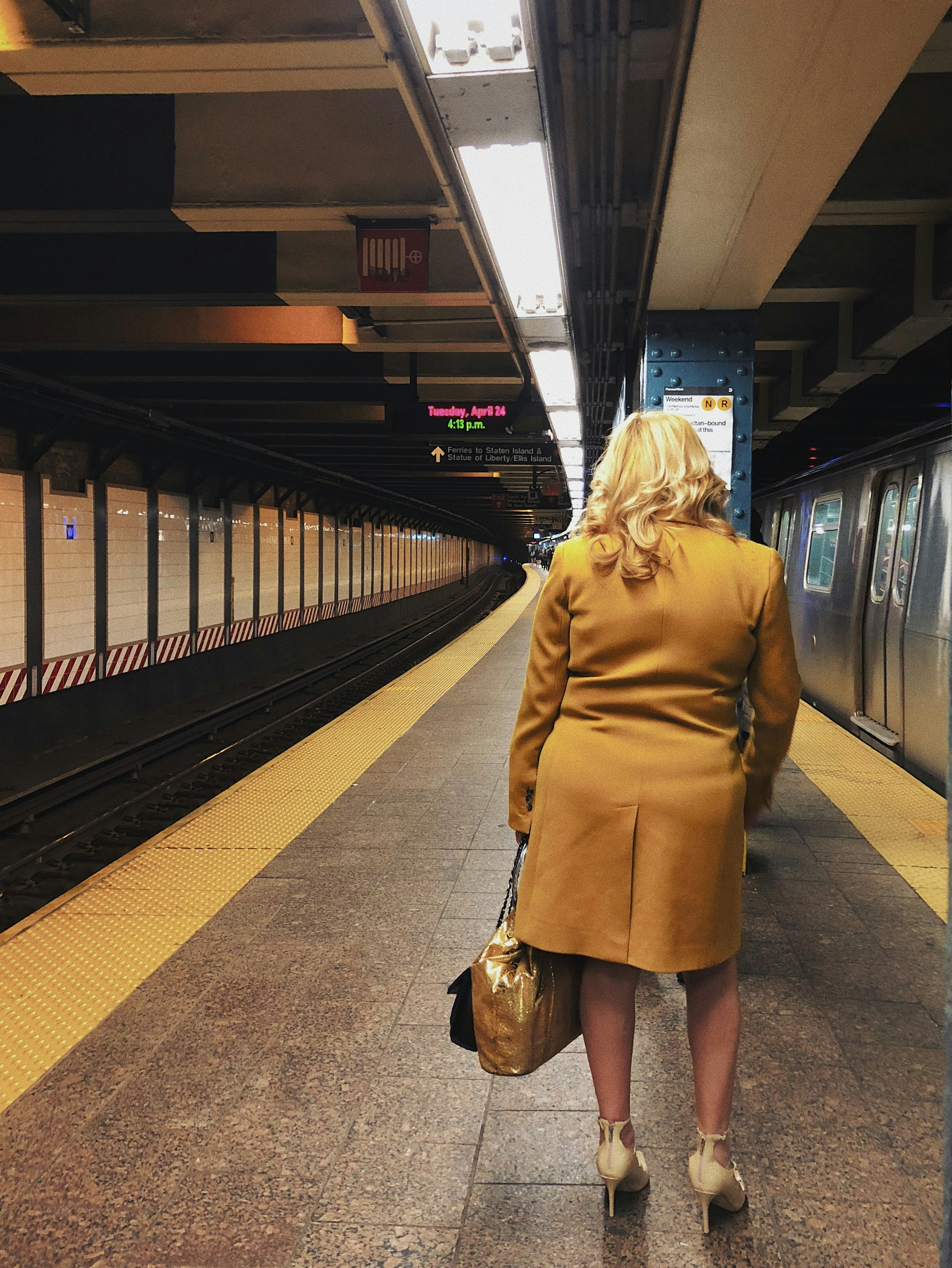 woman in brown coat standing on train station