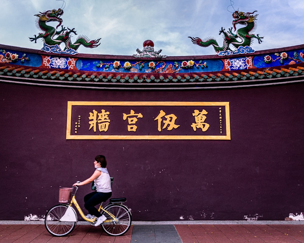 man in orange t-shirt riding on bicycle