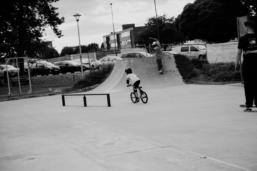 grayscale photo of man riding bicycle on road