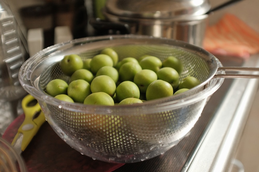 green round fruits in stainless steel bowl