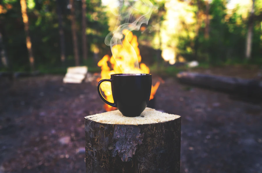 Coffee mug on a log beside a campfire in the woods