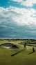 man in black shirt and pants standing on green grass field under white clouds and blue