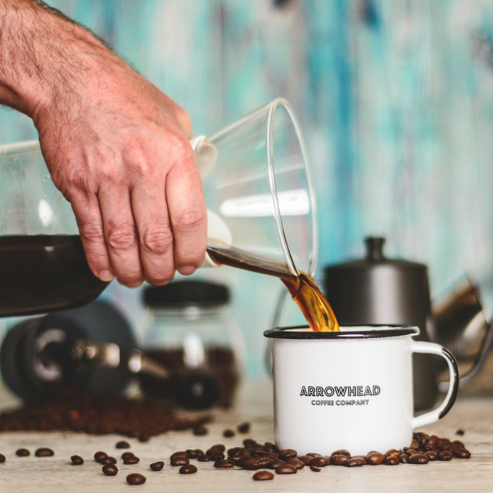 person pouring coffee on white ceramic mug