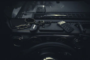 A compact dash cam beside a car key and sunglasses on a dashboard.