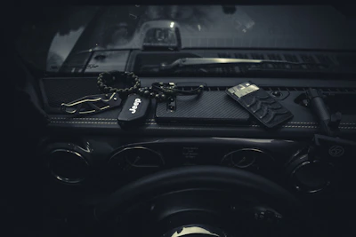 A compact, colorful keychain multitool resting on a car dashboard under soft sunlight.