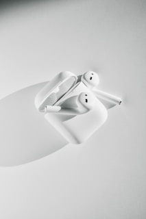 A pair of wireless earbuds displayed on a clean white surface with their charging case open
