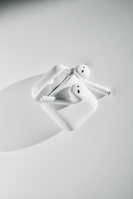 A pair of wireless earbuds on a soft surface.
