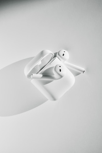 A pair of wireless earbuds on a soft surface.