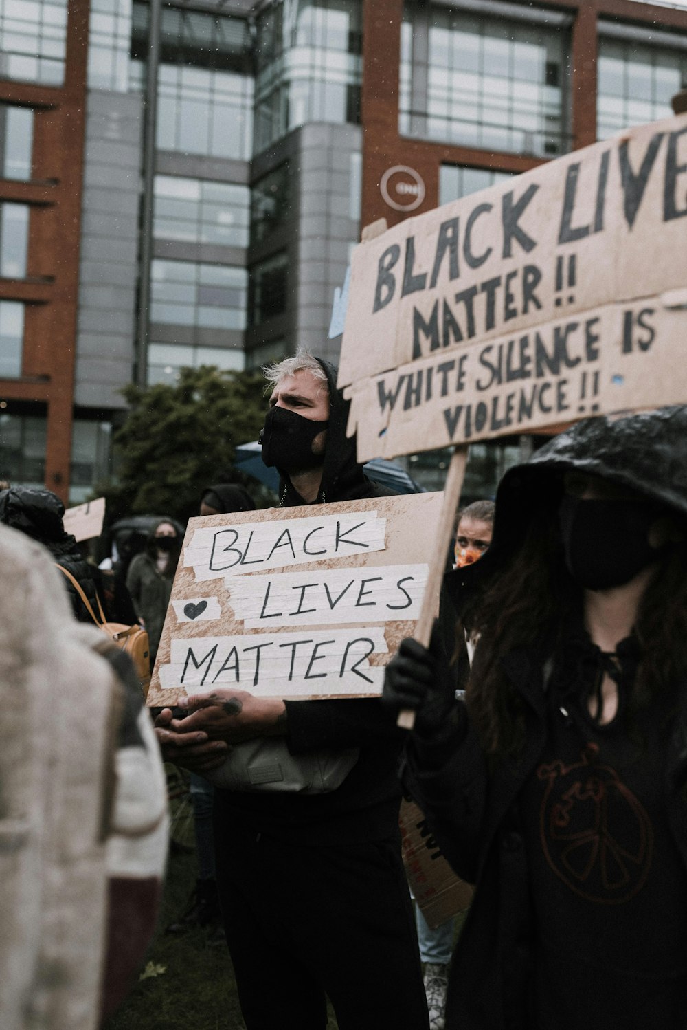 woman in black jacket holding white and black signage