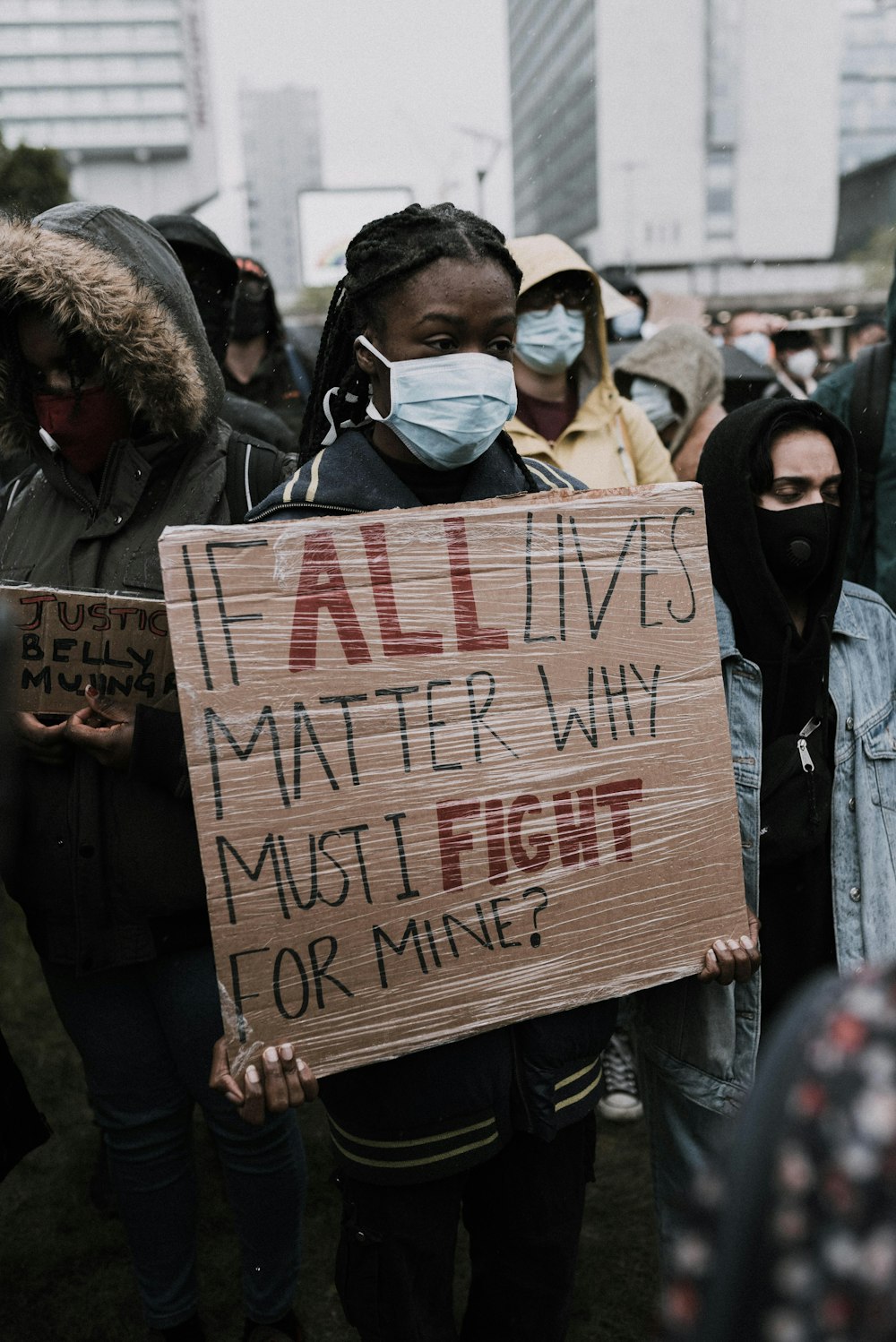 man in black jacket holding brown wooden signage