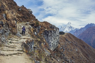 person in black jacket and black pants standing on rocky mountain during daytime