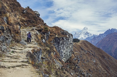 person in black jacket and black pants standing on rocky mountain during daytime