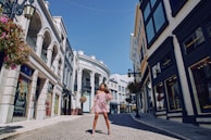 A model walking confidently along a sunlit cobblestone street in a flowing flamenco skirt.