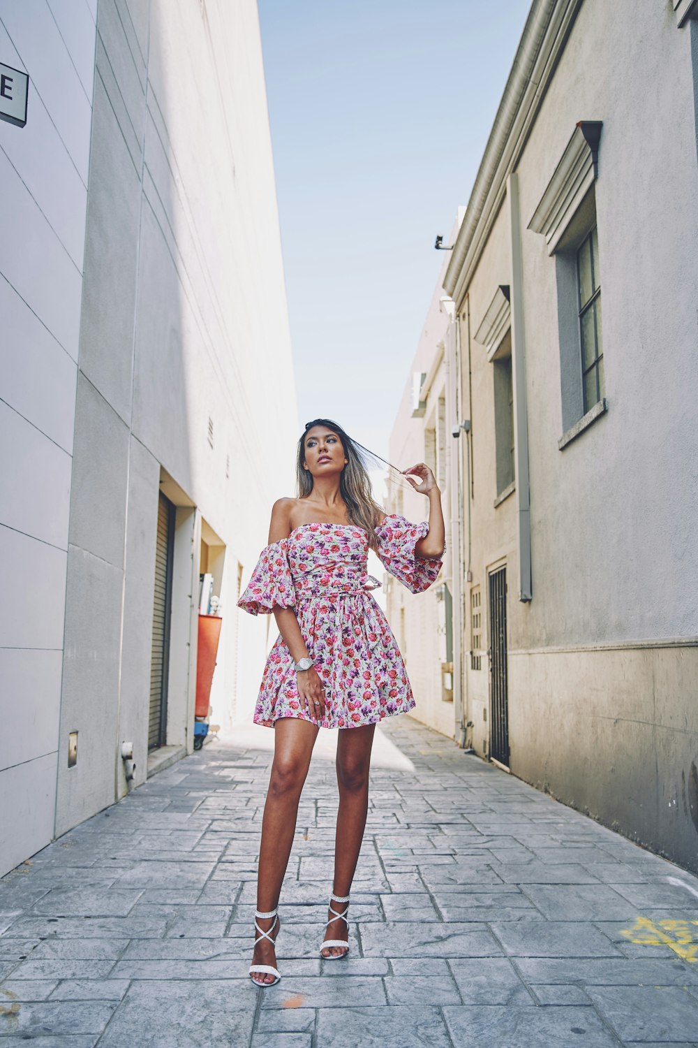 woman in pink and white floral dress standing on gray concrete floor during daytime