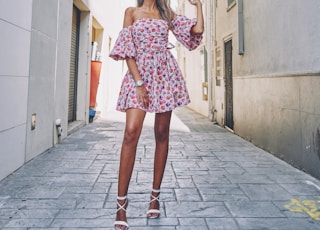 woman in pink and white floral dress standing on gray concrete floor during daytime