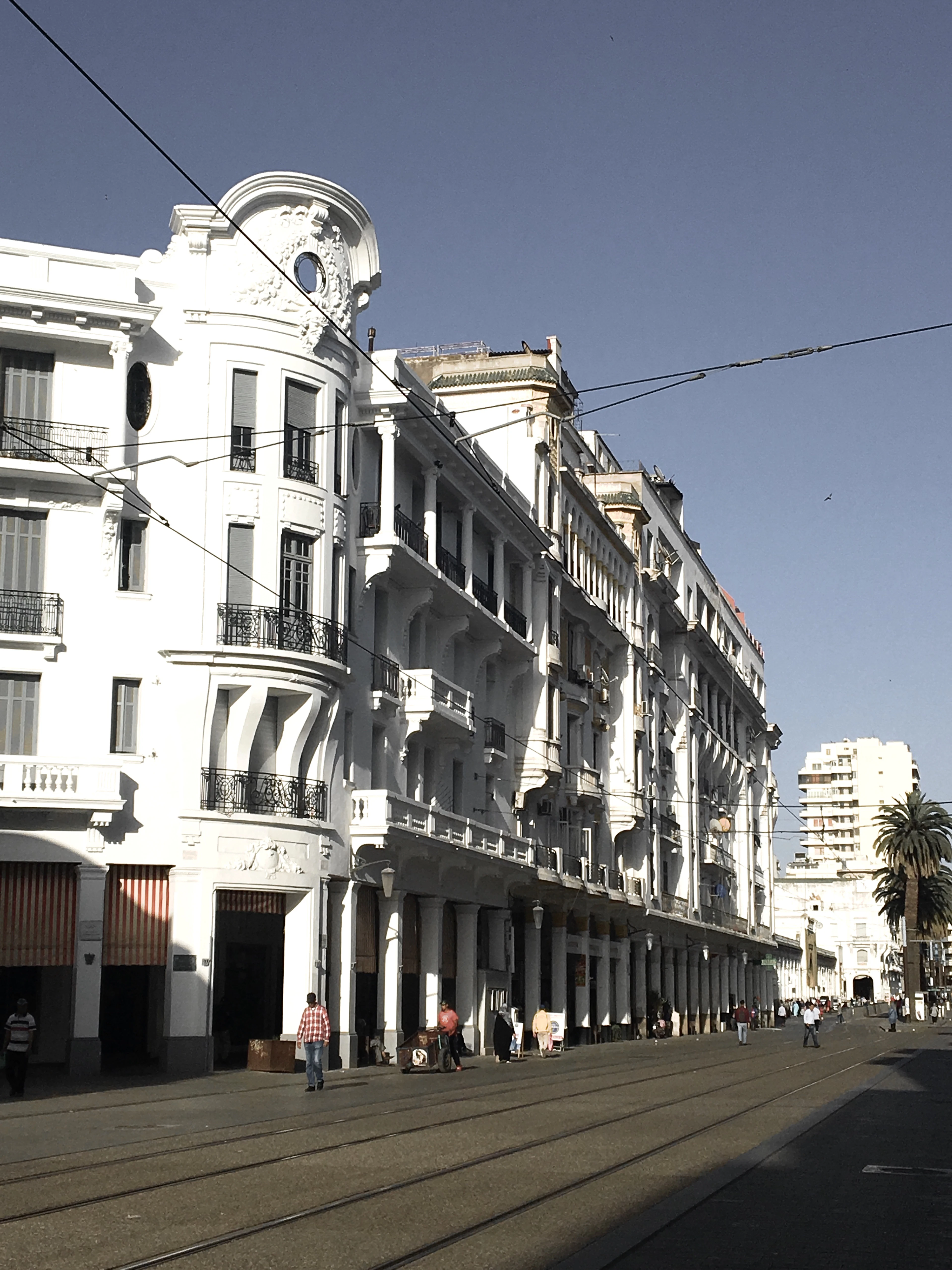 Ornate white art deco buildings line a tram-tracked boulevard in downtown Casablanca.