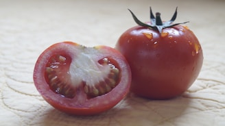 A close-up of a fresh tomato sliced in half, highlighting its juicy red interior.