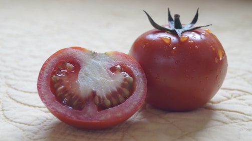 A close-up of a fresh tomato sliced in half, highlighting its juicy red interior.