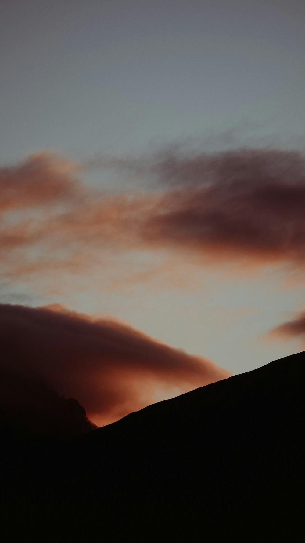 夕暮れ時の曇り空の下の山のシルエット