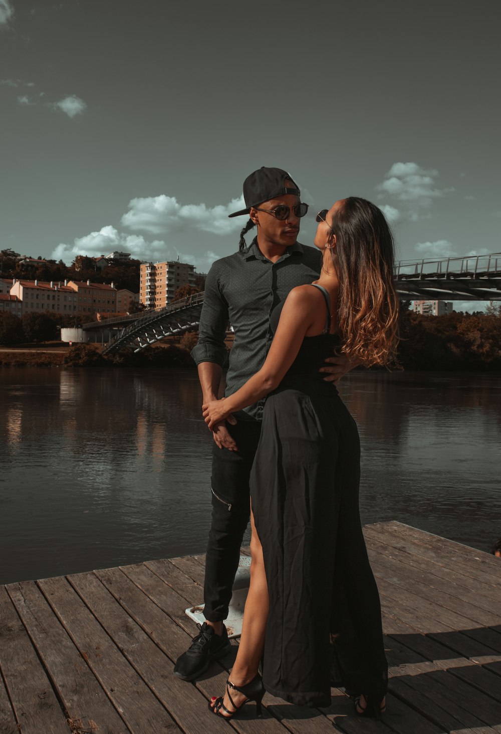 man and woman standing on wooden dock during sunset