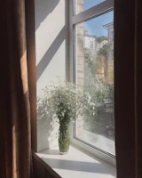 A serene scene showing handmade clay vases with fresh flowers on a sunlit windowsill.