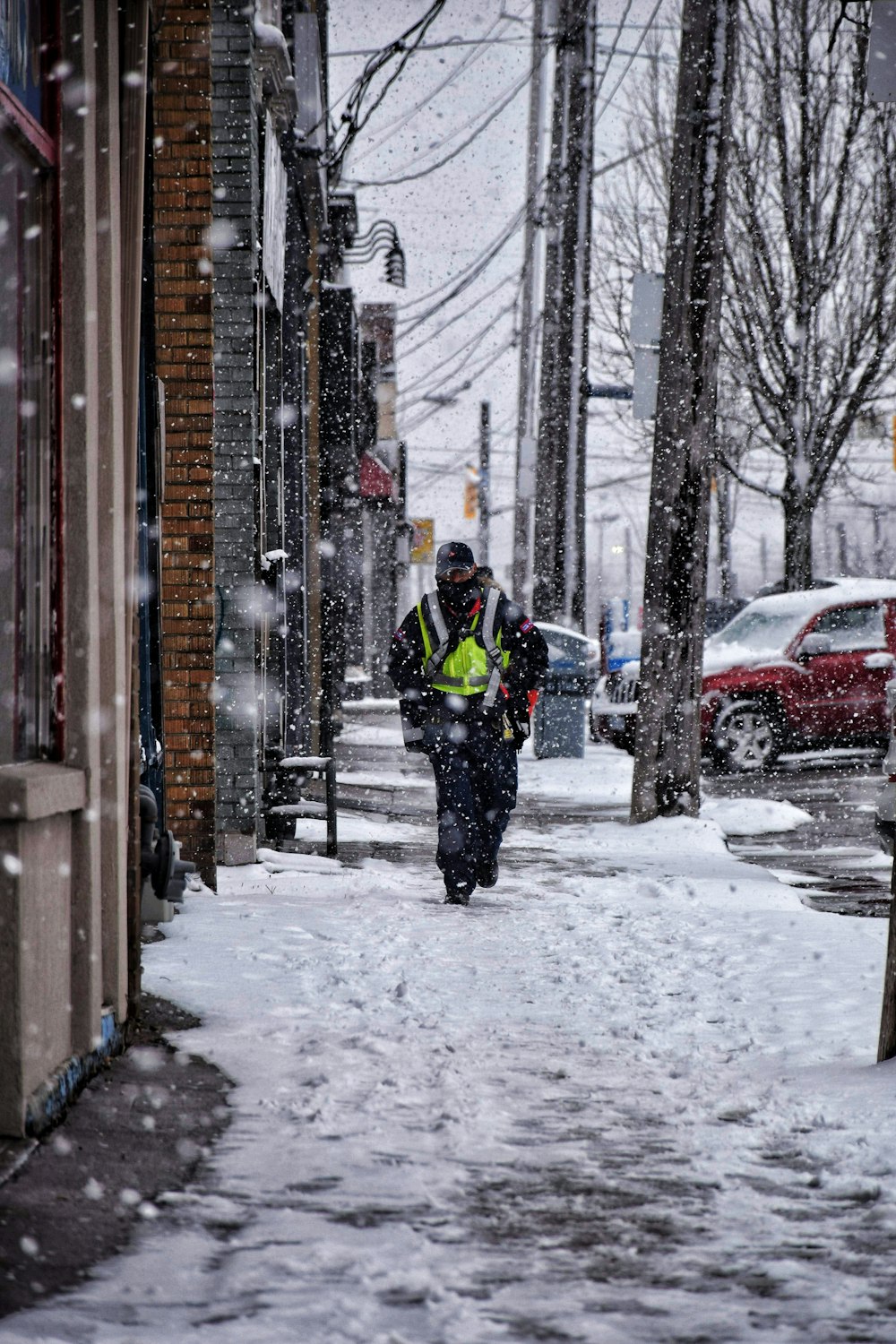 man in green jacket and black pants walking on snow covered road during daytime