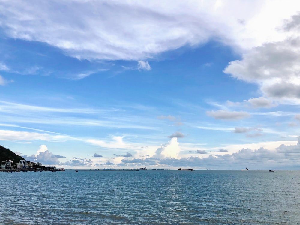 body of water under blue sky and white clouds during daytime