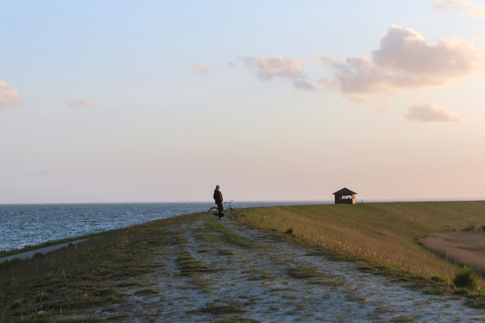 person standing on green grass field near body of water during daytime