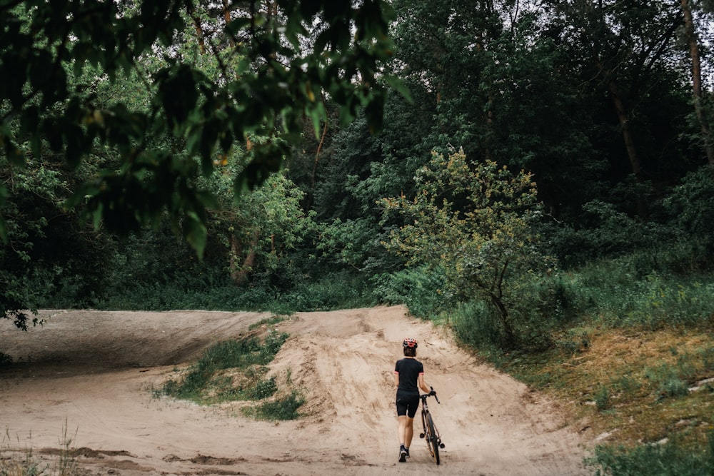 man in black shirt riding bicycle on dirt road during daytime