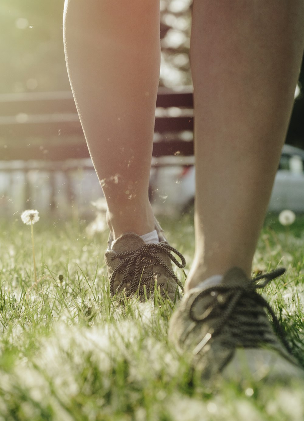 person in black and white sneakers standing on green grass field during daytime