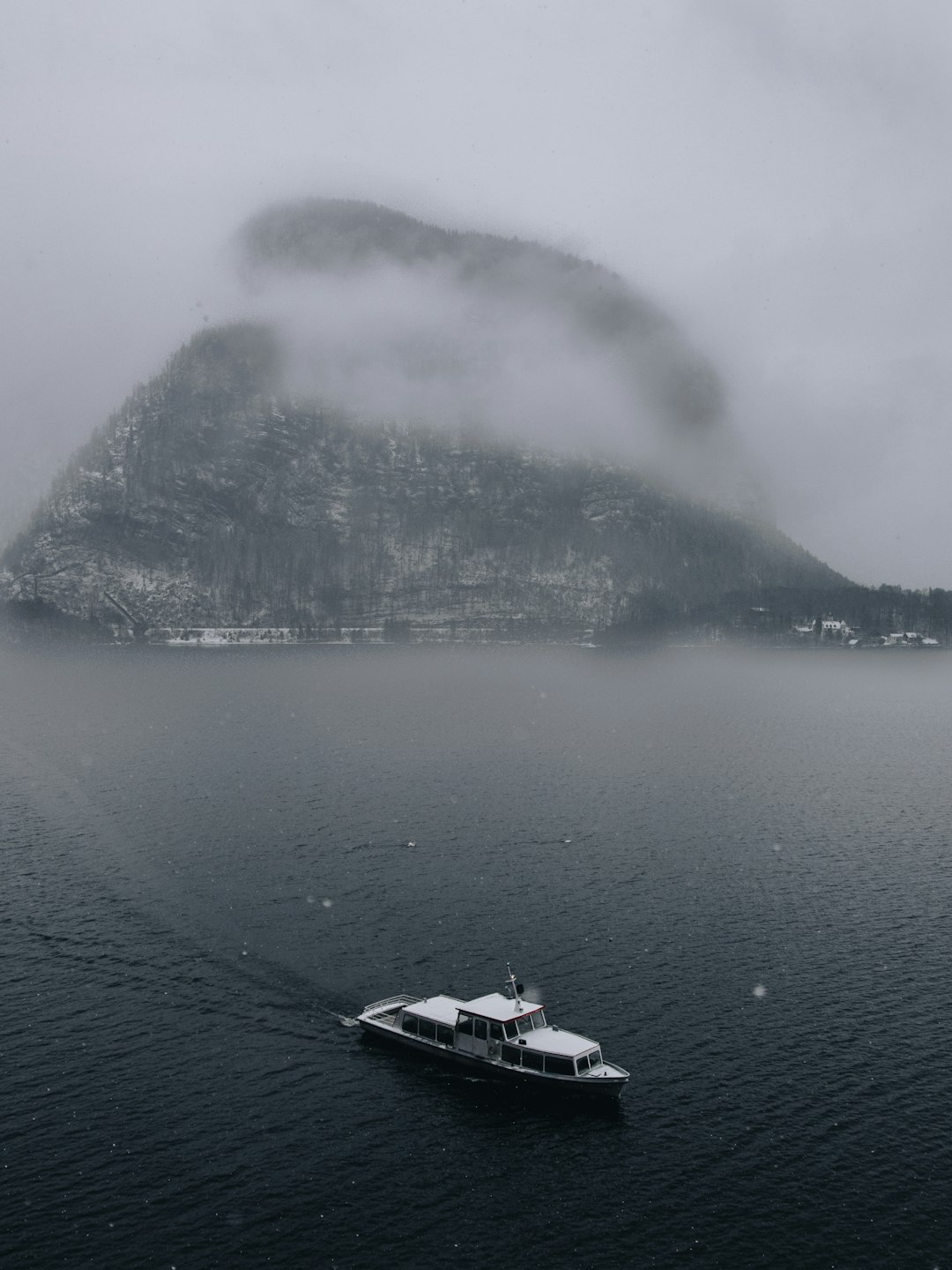 white boat on body of water near mountain during daytime