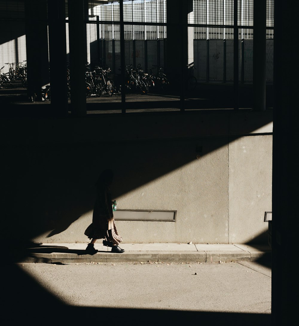 girl in black jacket and pants walking on sidewalk during daytime