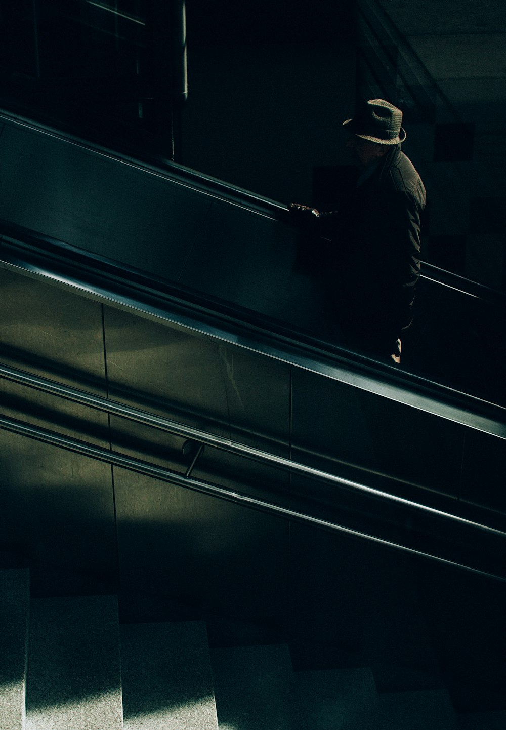 man in black jacket and black pants standing on escalator