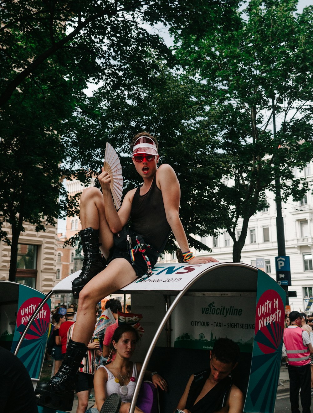 man in black tank top wearing black sunglasses sitting on white and red bicycle during daytime