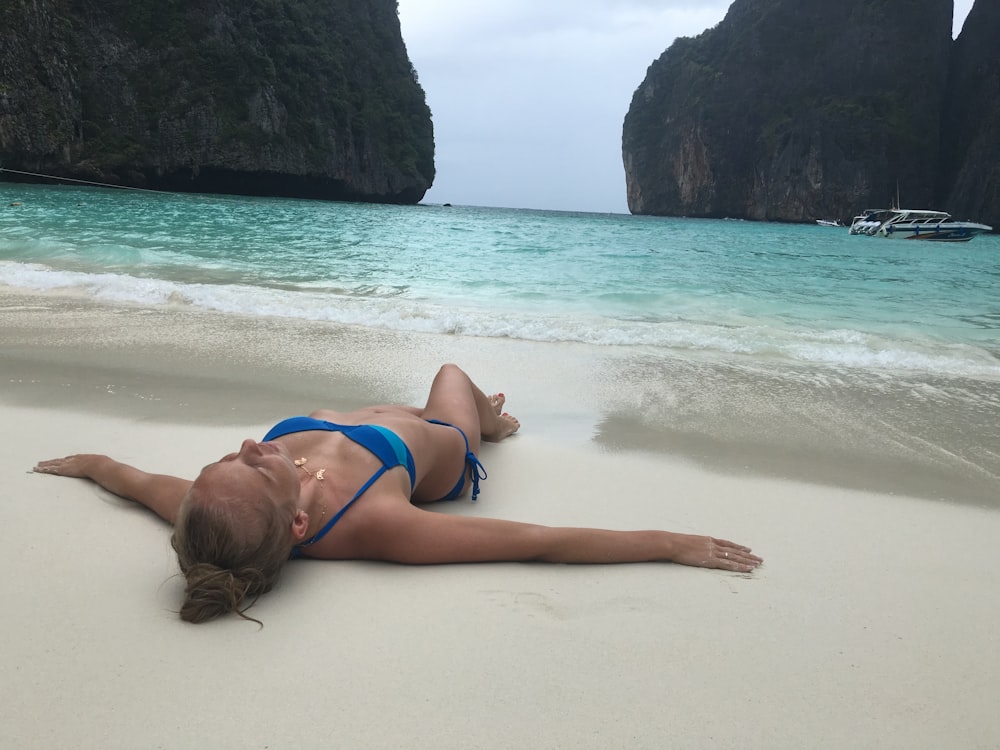 mulher no biquíni azul deitado na praia durante o dia