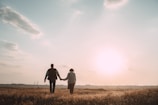 A serene couple walking hand in hand through a sunset-lit path.