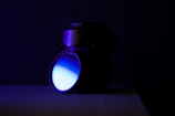 Close-up of a camera lens reflecting a deep blue light in a dark room.