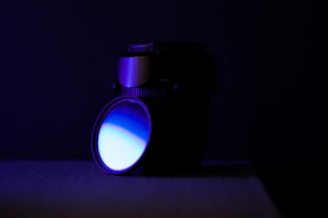 Close-up of a high-precision optical lens reflecting blue light in a clean industrial setting