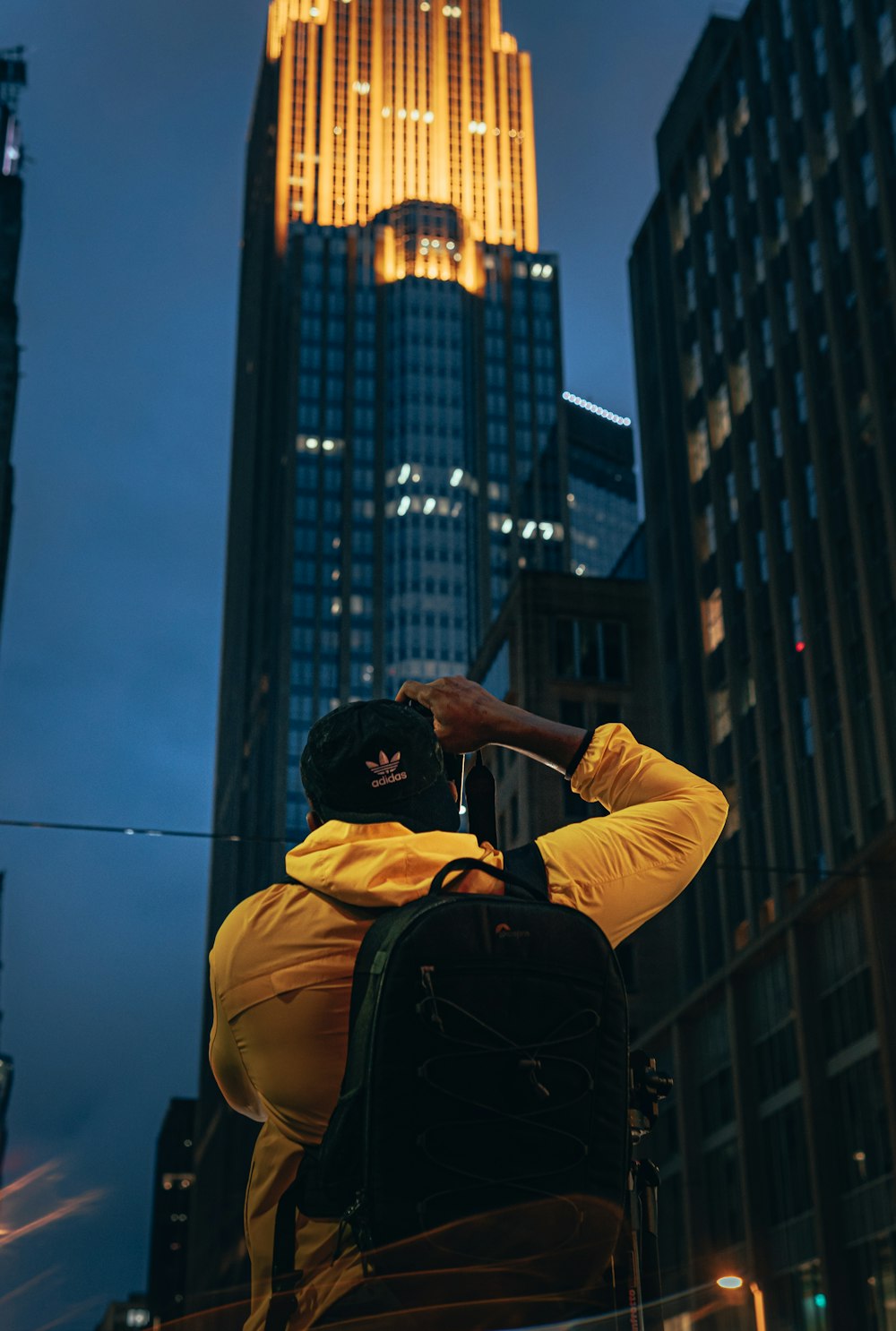 man in yellow hoodie and black backpack standing on top of building during daytime