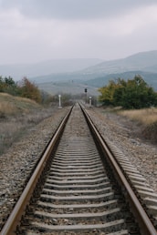 train rail near green grass field during daytime