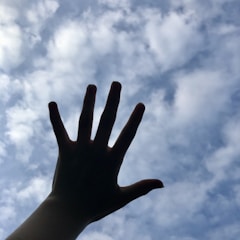 Hands lifted toward the sky with light breaking through dark clouds above.