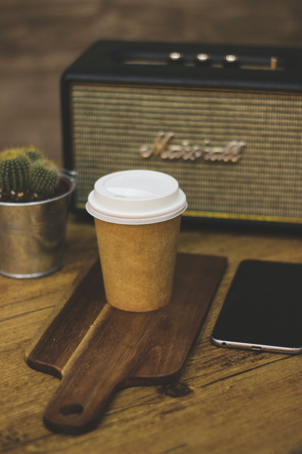 white and brown coffee cup beside silver iphone 6 on brown wooden table