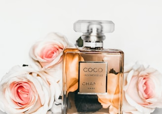 gold perfume bottle beside pink rose