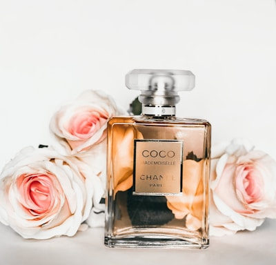 gold perfume bottle beside pink rose