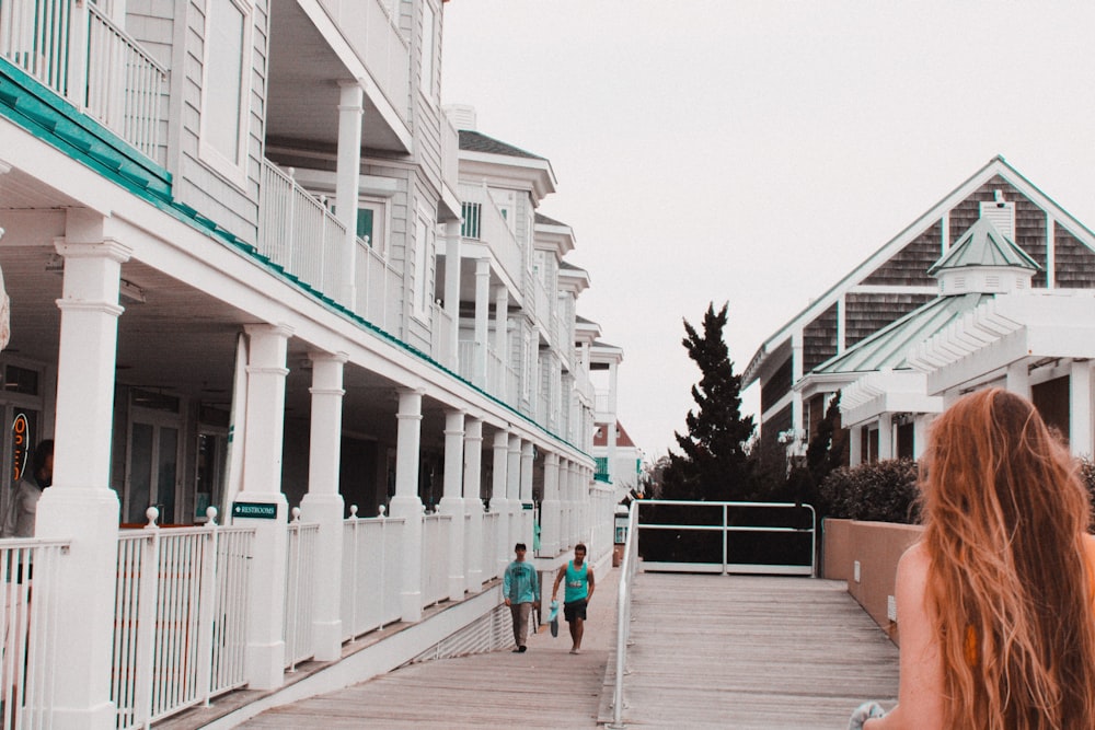 2 women walking on sidewalk near white concrete building during daytime